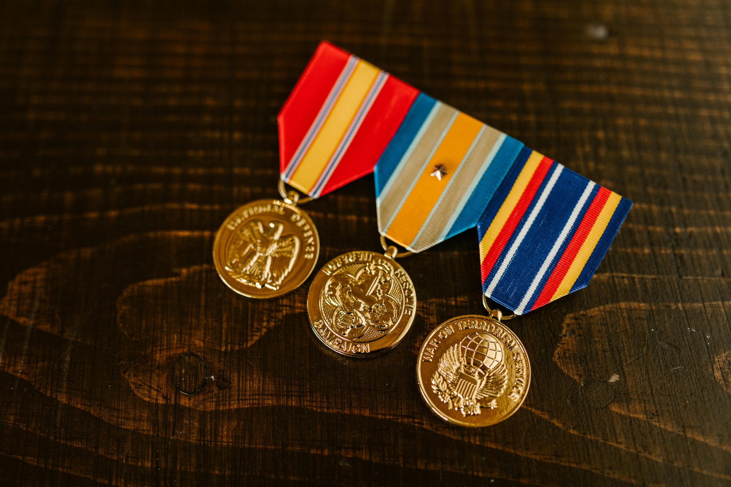 Close-up of gold military medals with ribbons on a wooden table.